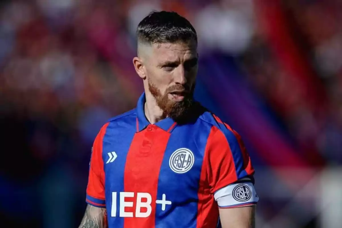 Futbolista con barba y cabello corto usando el uniforme azul y rojo de San Lorenzo durante un partido