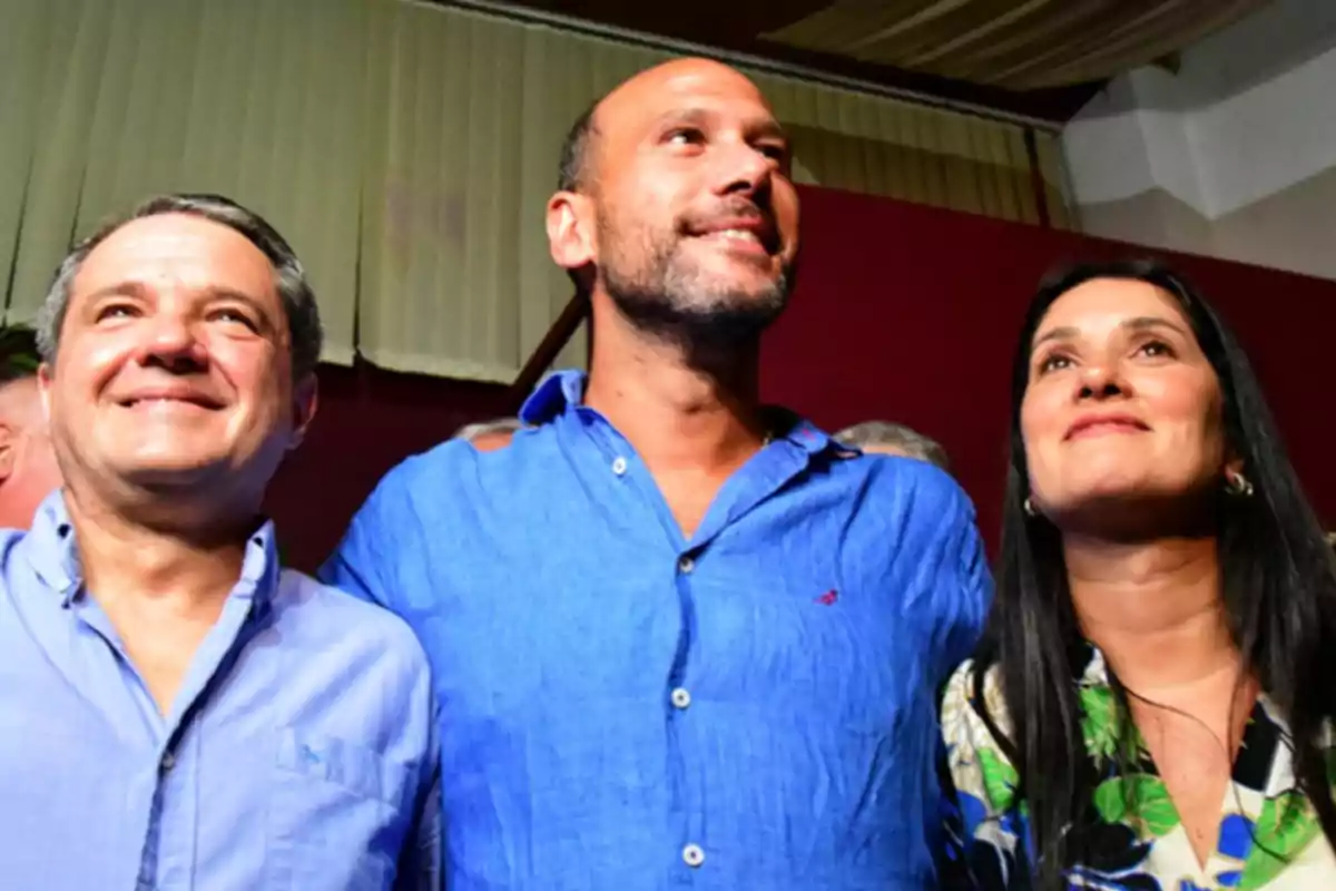 Tres personas sonrientes mirando hacia arriba en un evento en interiores. Tres personas sonrientes mirando hacia arriba en un evento en interiores.