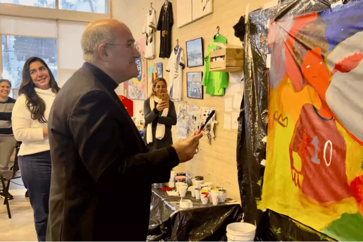 Un grupo de personas observa a un hombre mientras pinta un cuadro en un taller de arte.