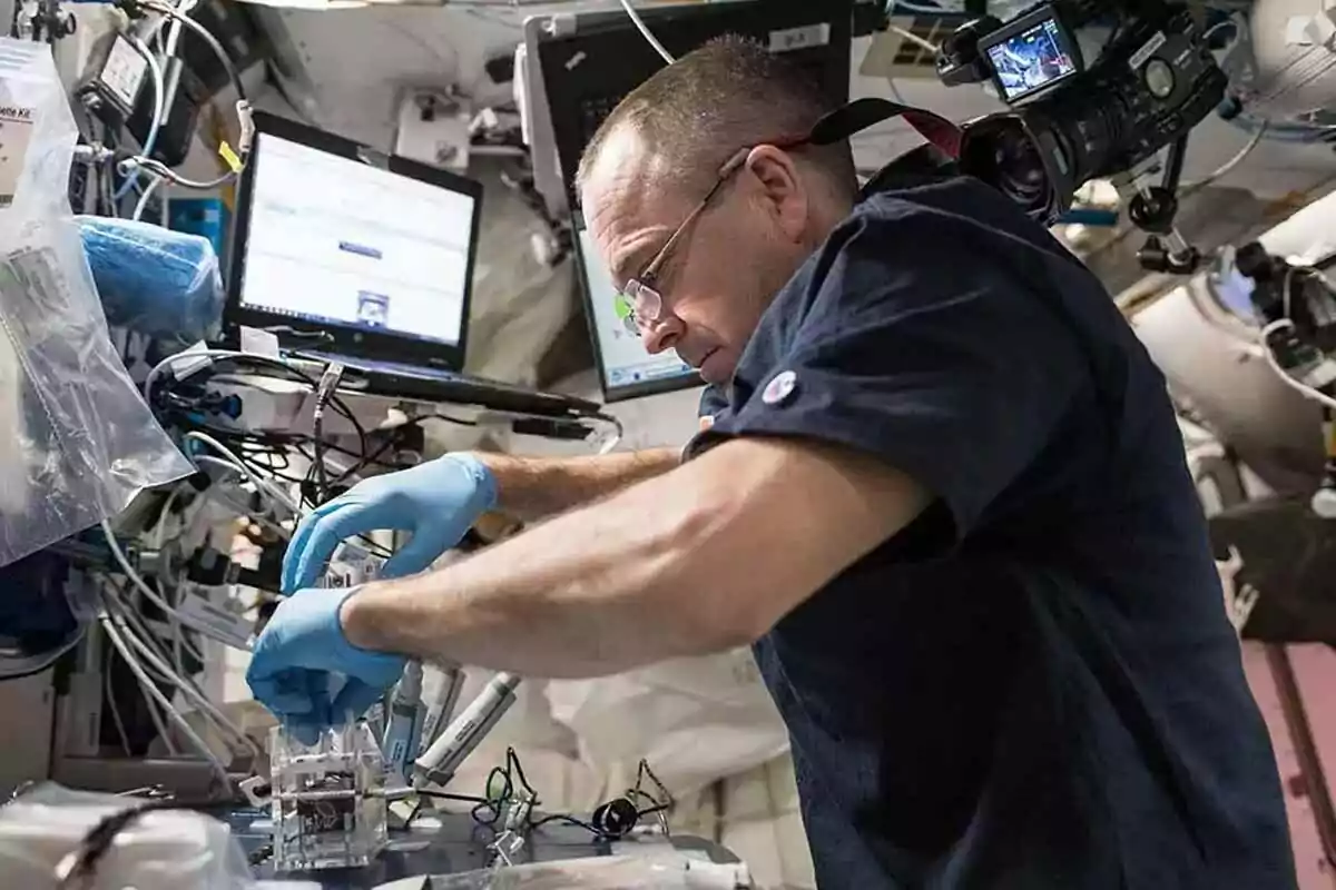 Un hombre con guantes azules trabaja en un experimento en un entorno lleno de equipos tecnológicos y pantallas. Un hombre con guantes azules trabaja en un experimento en un entorno lleno de equipos tecnológicos y pantallas.