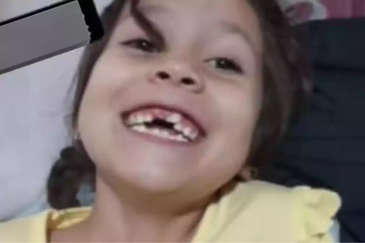 Una niña sonriente mostrando sus dientes mientras está acostada.