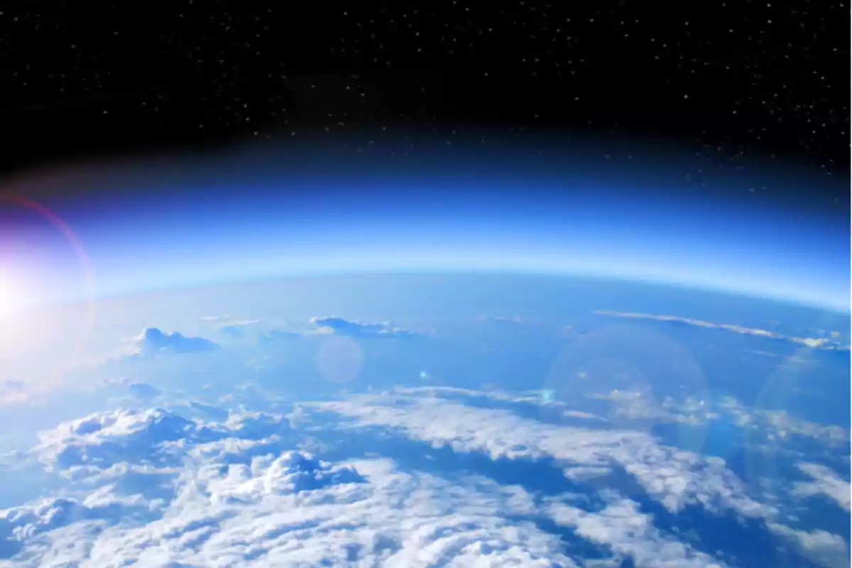 Vista del horizonte terrestre desde el espacio con nubes y el resplandor del sol.