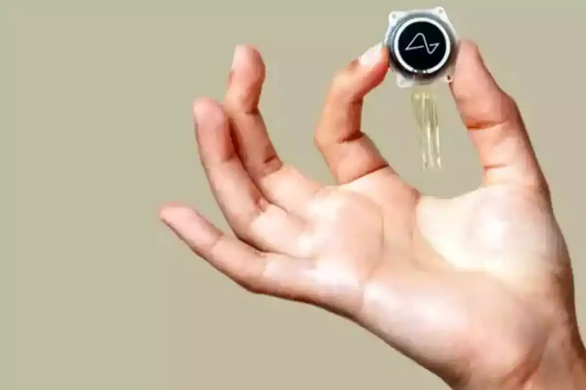 Una mano sosteniendo un pequeño dispositivo circular con cables. Una mano sosteniendo un pequeño dispositivo circular con cables.