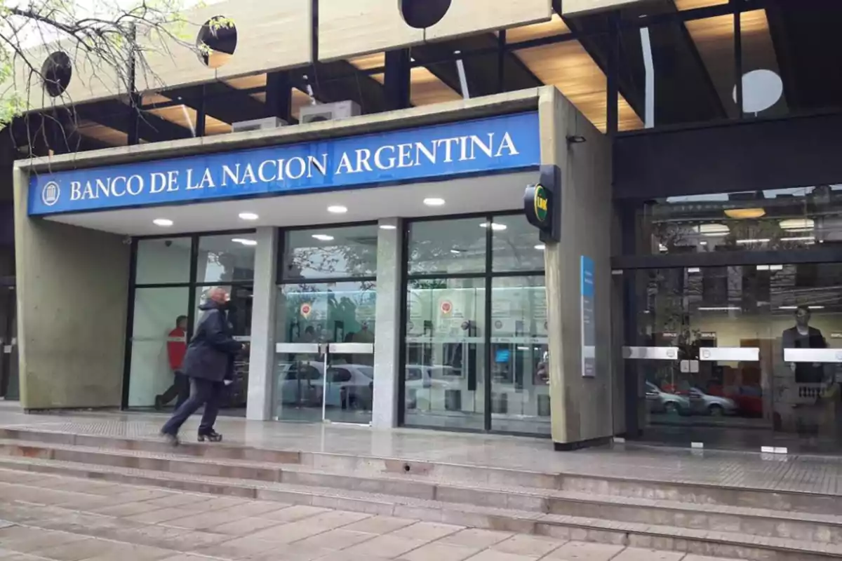 Una persona caminando hacia la entrada del Banco de la Nación Argentina.