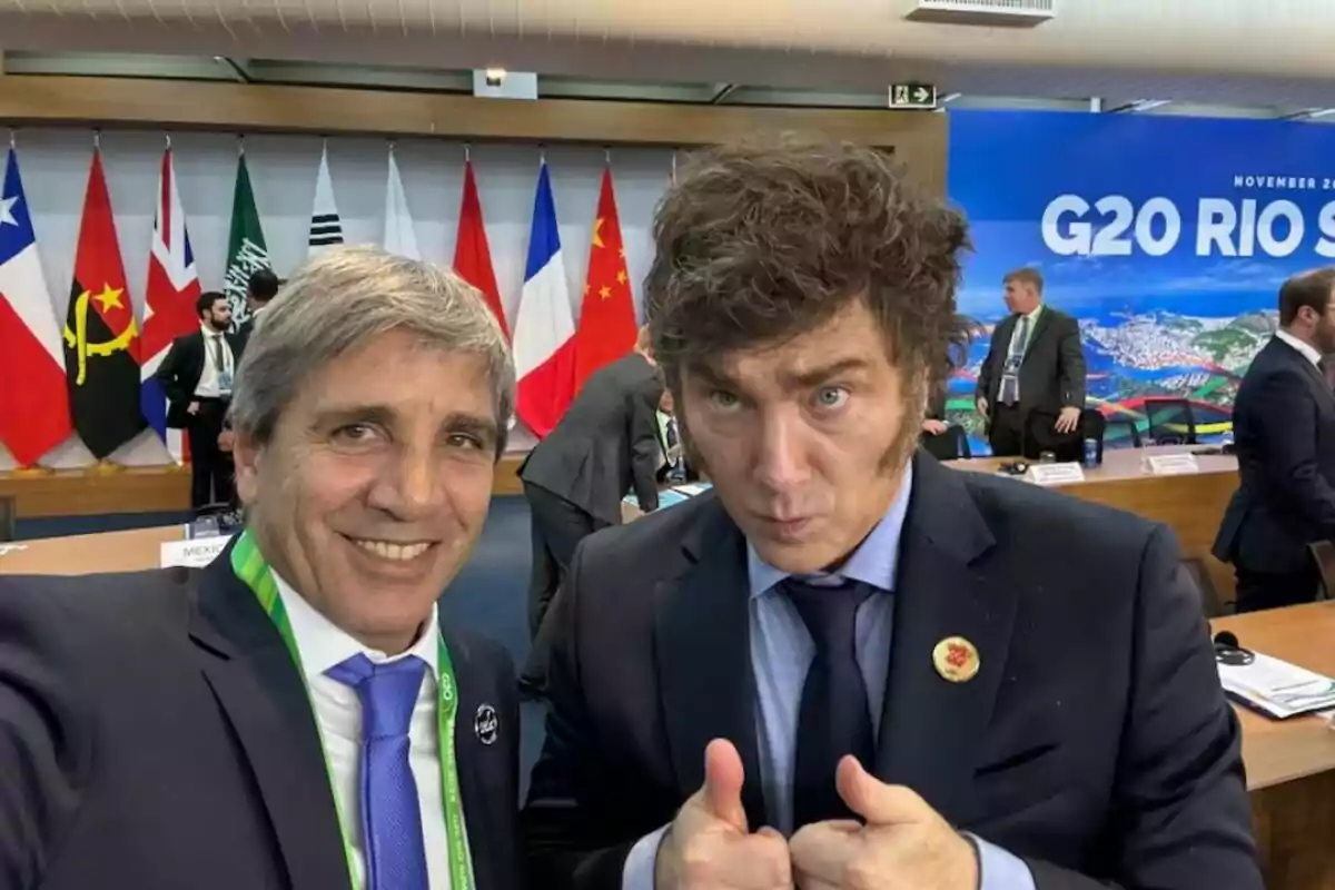 Two people pose for a photo at a G20 conference with various flags in the background.