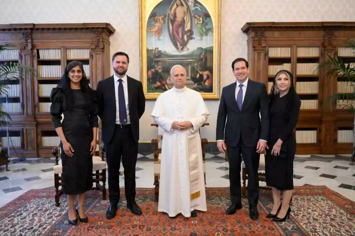 A group of people posing in a room with bookshelves and a religious painting on the wall.
