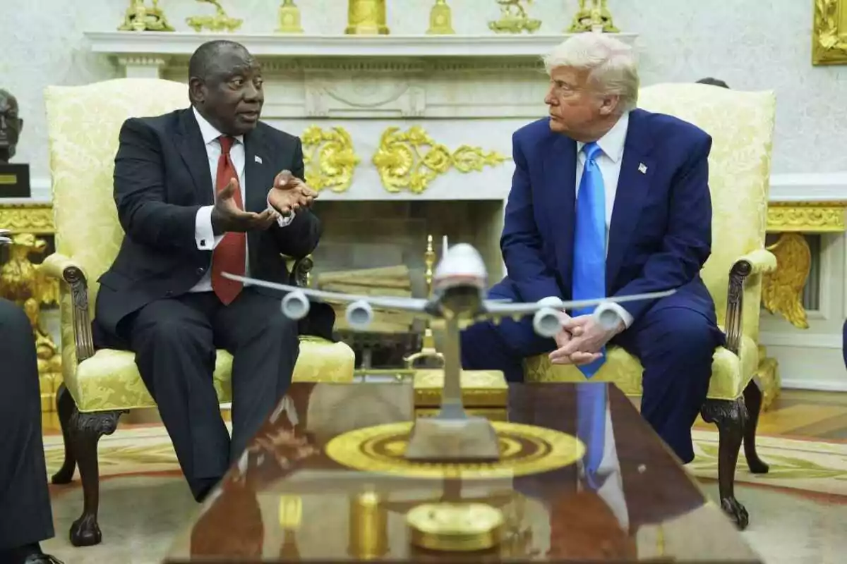 Two men sitting in elegant chairs in a room decorated with golden details and a model airplane on the table in front of them. Two men sitting in elegant chairs in a room decorated with golden details and a model airplane on the table in front of them.