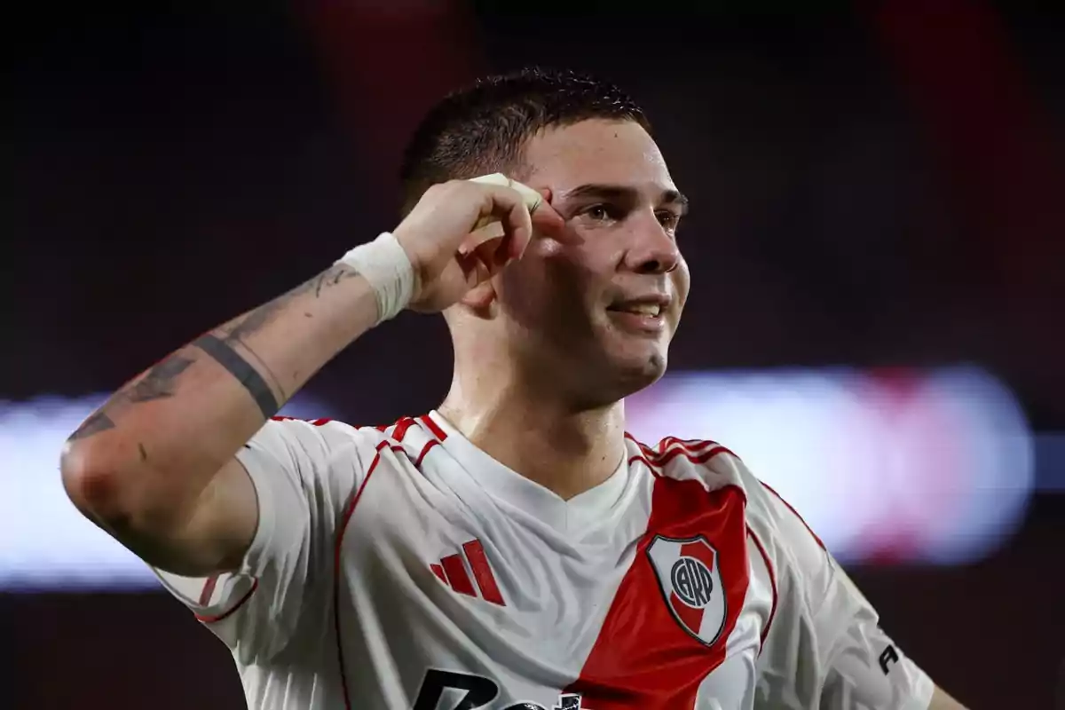 Un jugador de fútbol con uniforme blanco y rojo celebra en el campo. Un jugador de fútbol con uniforme blanco y rojo celebra en el campo.