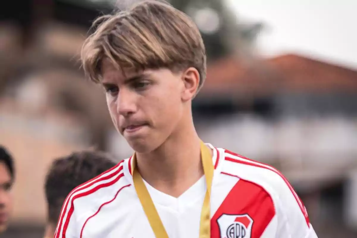 Young man with a white and red soccer jersey and a gold medal. Young man with a white and red soccer jersey and a gold medal.