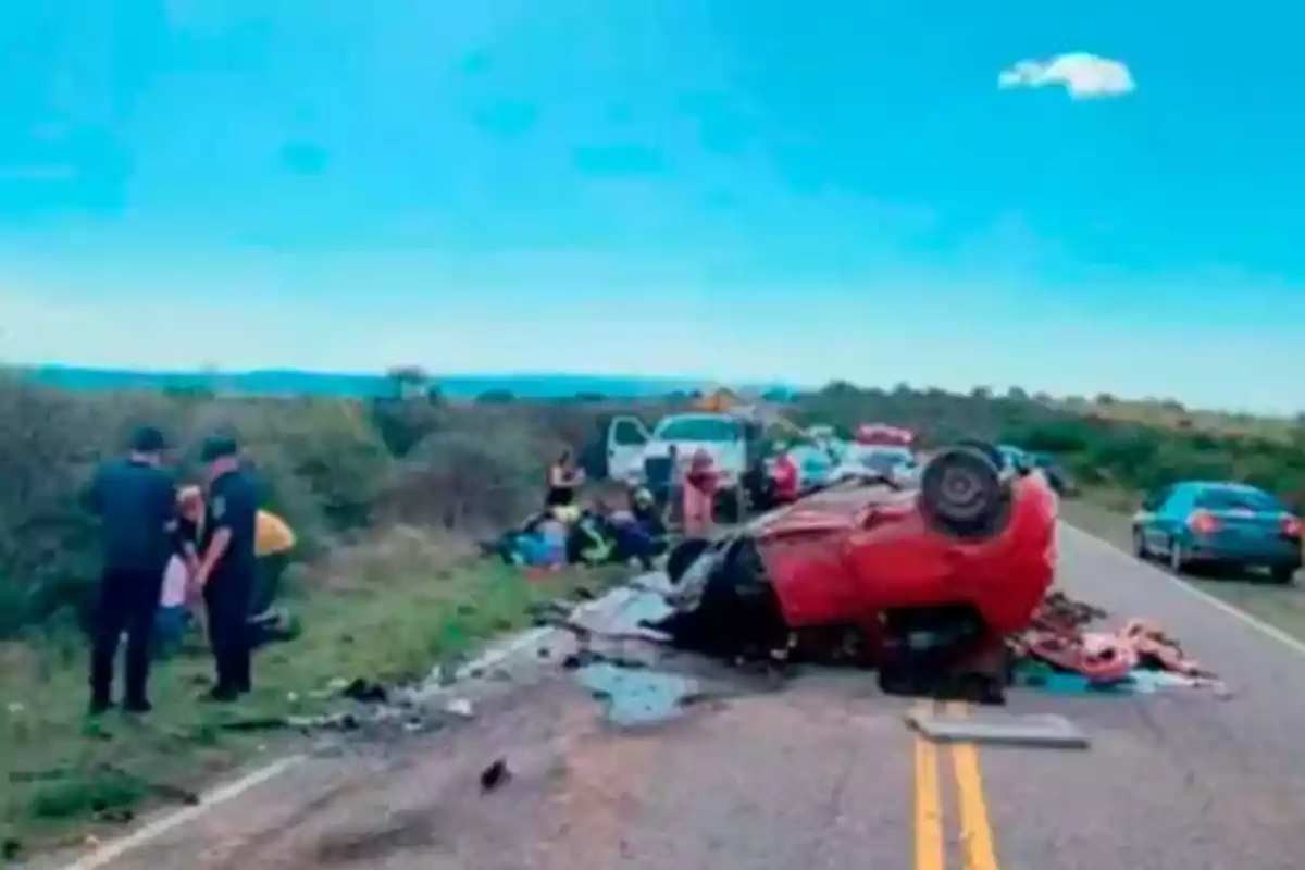 Overturned red car on a road with people and emergency vehicles around attending to the situation. Overturned red car on a road with people and emergency vehicles around attending to the situation.
