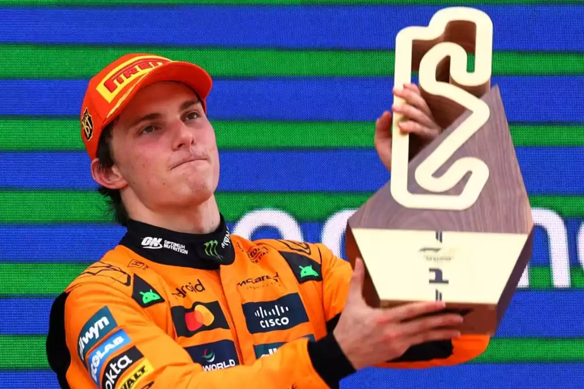 Auto racing driver in an orange uniform and cap holding a trophy on the podium at a competition Auto racing driver in an orange uniform and cap holding a trophy on the podium at a competition