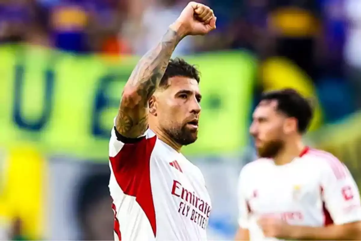 Futbolista con uniforme blanco y rojo levantando el puño en señal de celebración durante un partido