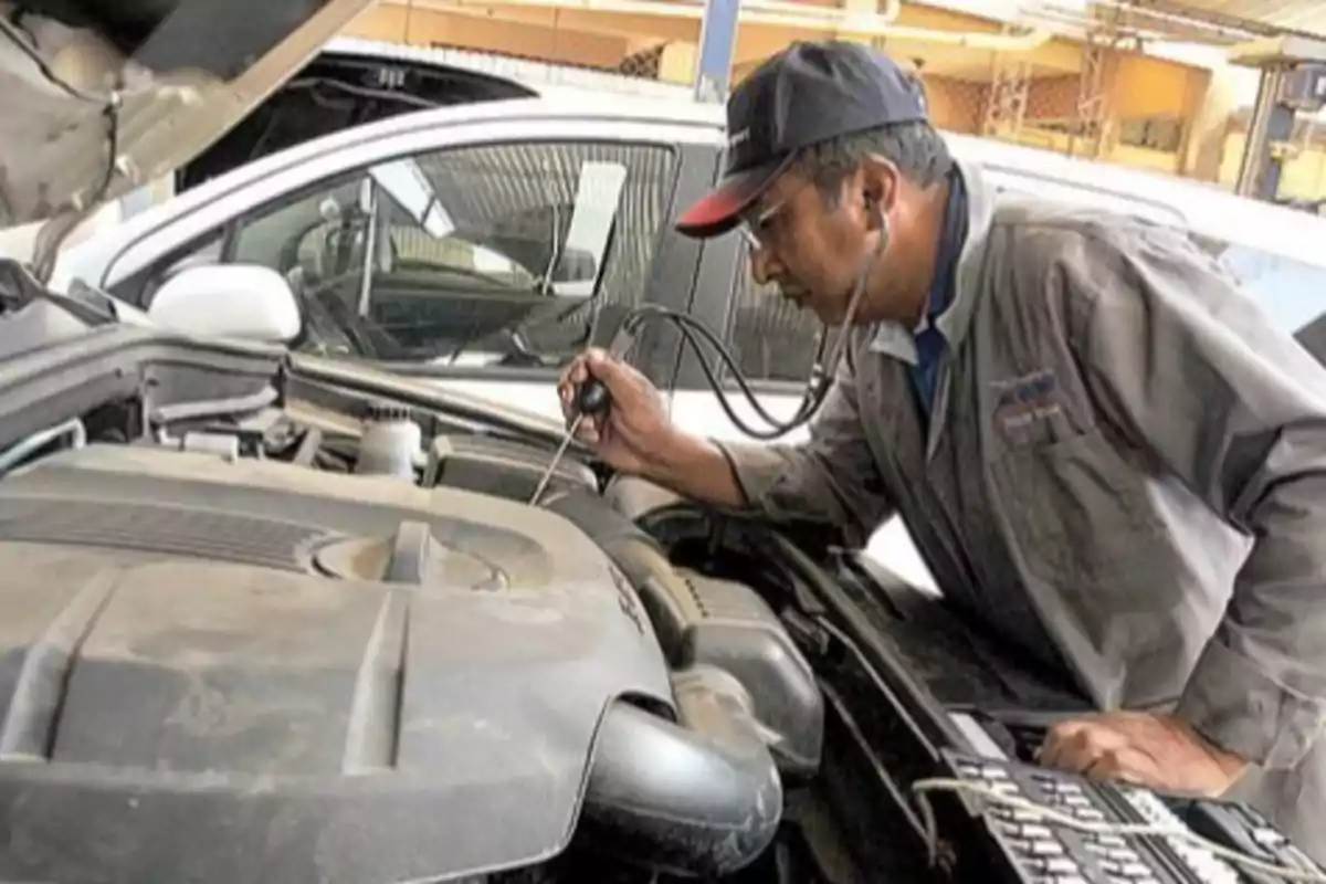 A mechanic checks a car engine with a stethoscope in a workshop.