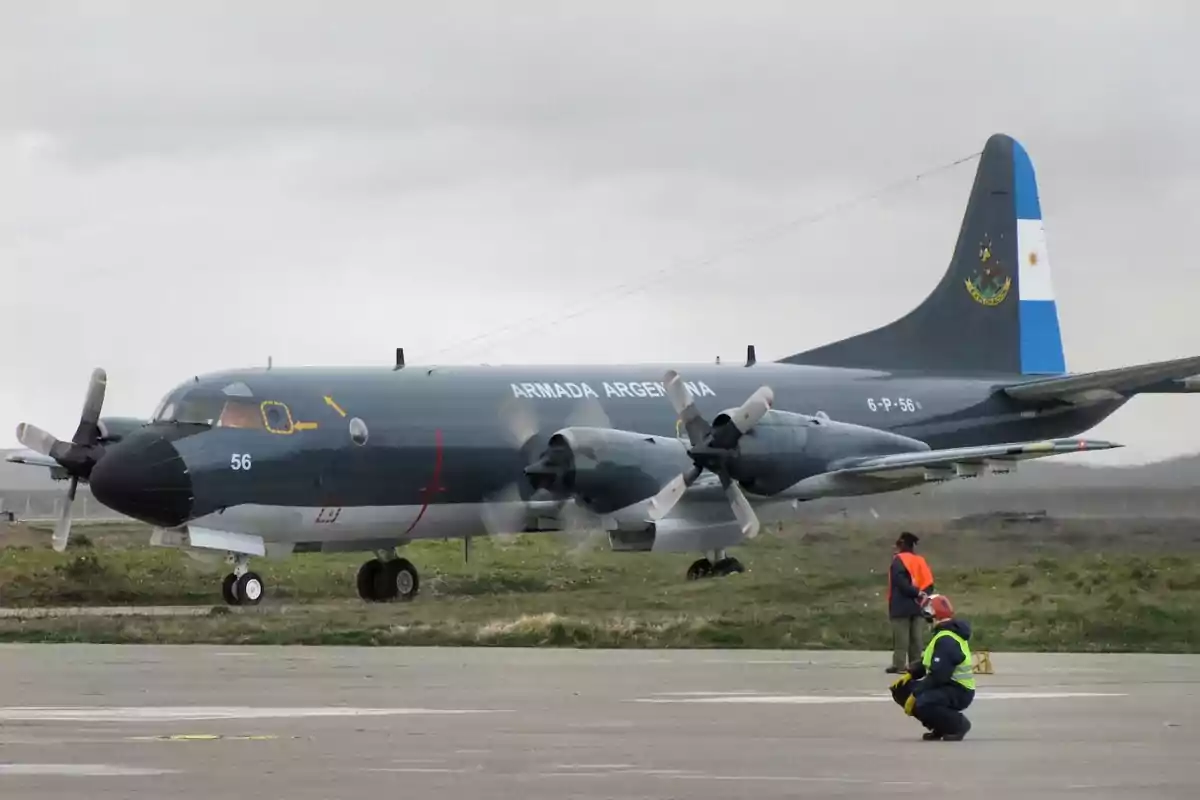 Avión militar de la Armada Argentina en una pista con dos personas en uniforme cerca del avión Avión militar de la Armada Argentina en una pista con dos personas en uniforme cerca del avión