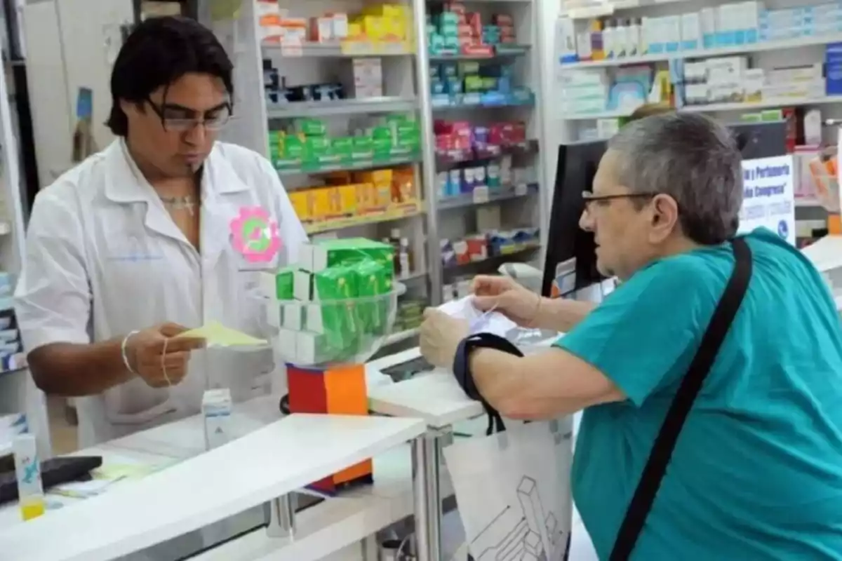 Un farmacéutico atiende a un cliente en una farmacia, revisando una receta mientras el cliente sostiene una bolsa.