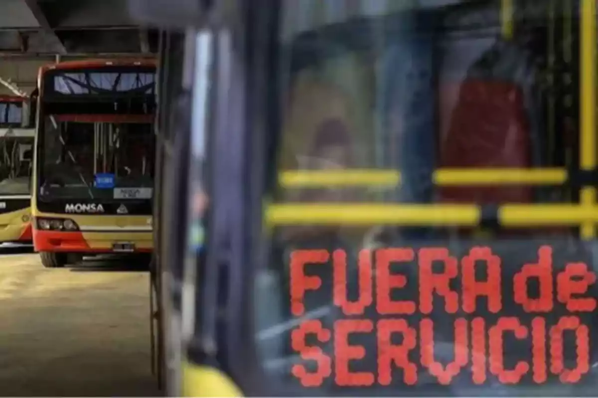 Un autobús con un letrero que indica "Fuera de servicio" en un estacionamiento junto a otros autobuses.