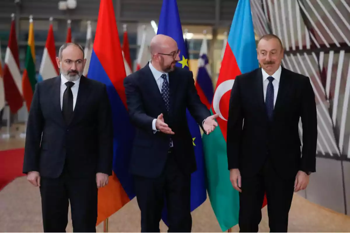 Tres hombres de traje posan frente a las banderas de Armenia, la Unión Europea y Azerbaiyán en un entorno formal.