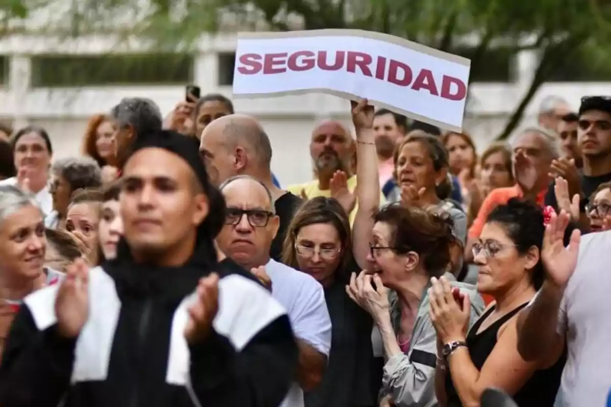 Un grupo de personas participa en una manifestación y una mujer sostiene un cartel que dice seguridad Un grupo de personas participa en una manifestación y una mujer sostiene un cartel que dice seguridad