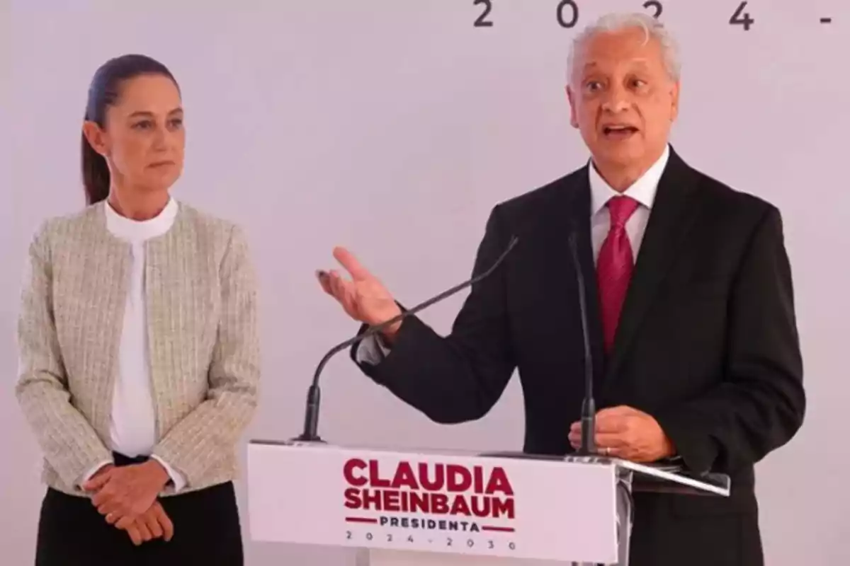 Dos personas en un evento político, una de ellas está hablando en un podio con un micrófono.