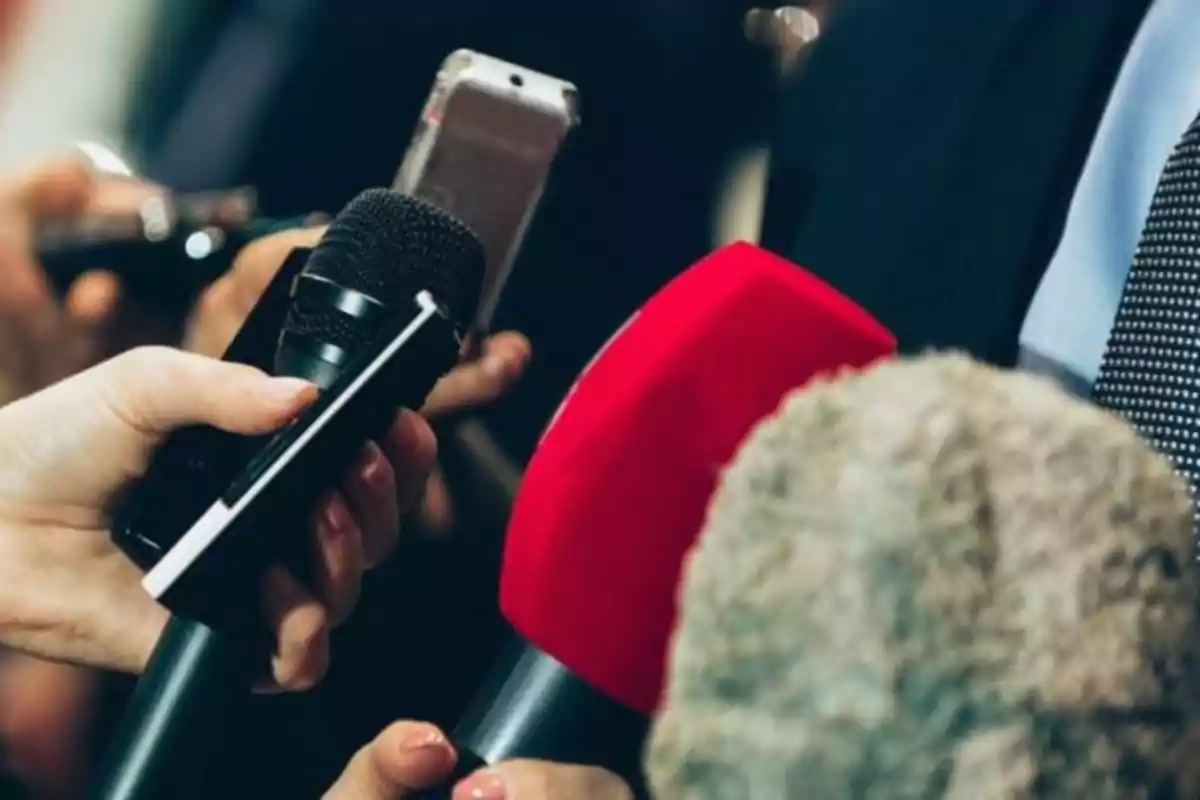 Varias manos sostienen micrófonos y grabadoras durante una entrevista. Varias manos sostienen micrófonos y grabadoras durante una entrevista.