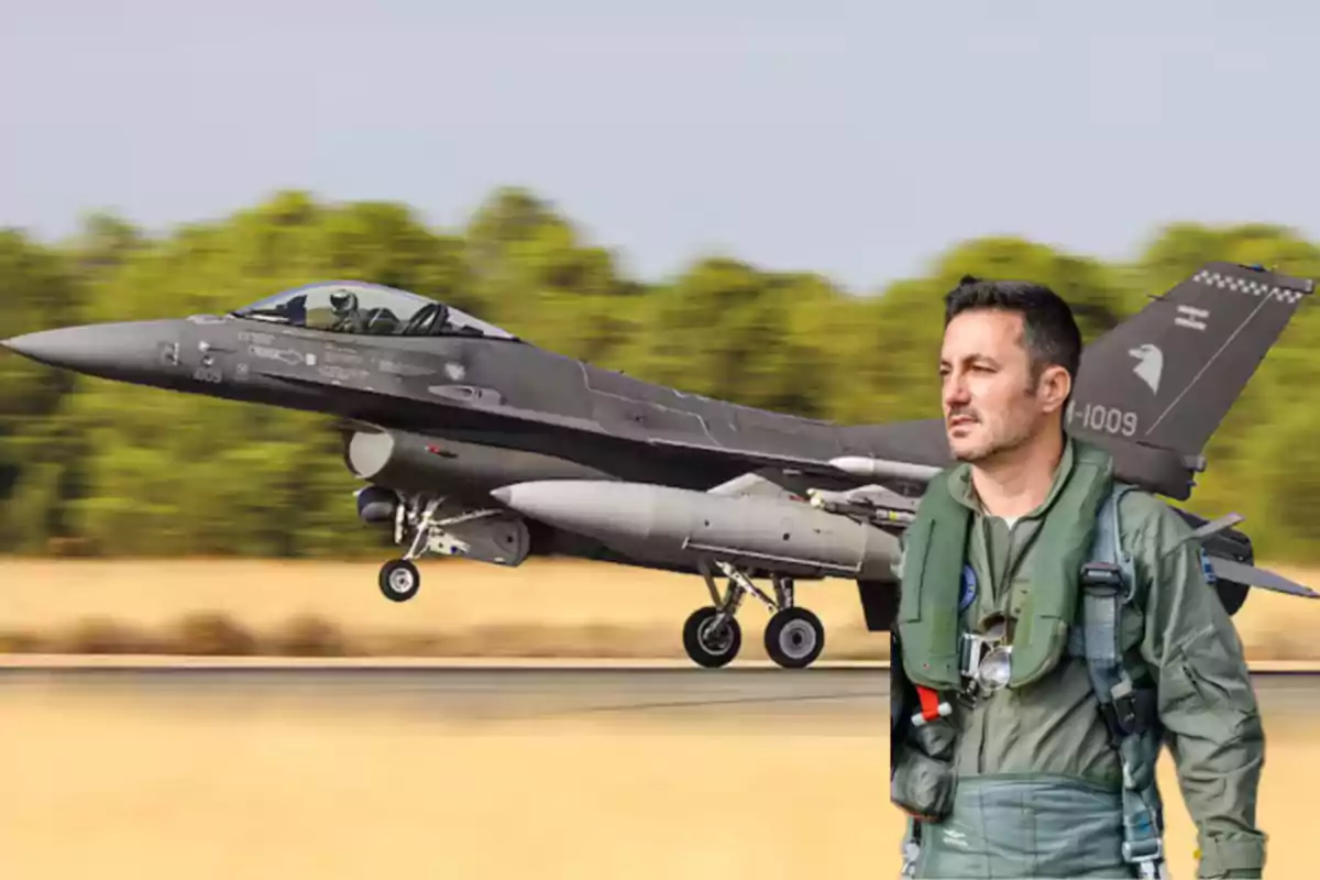 Piloto de combate con uniforme militar de pie frente a un avión de combate en una pista de aterrizaje.