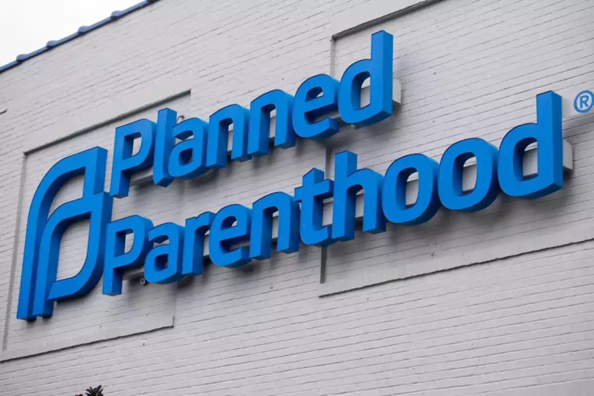 Un letrero azul de Planned Parenthood en la pared de un edificio blanco.