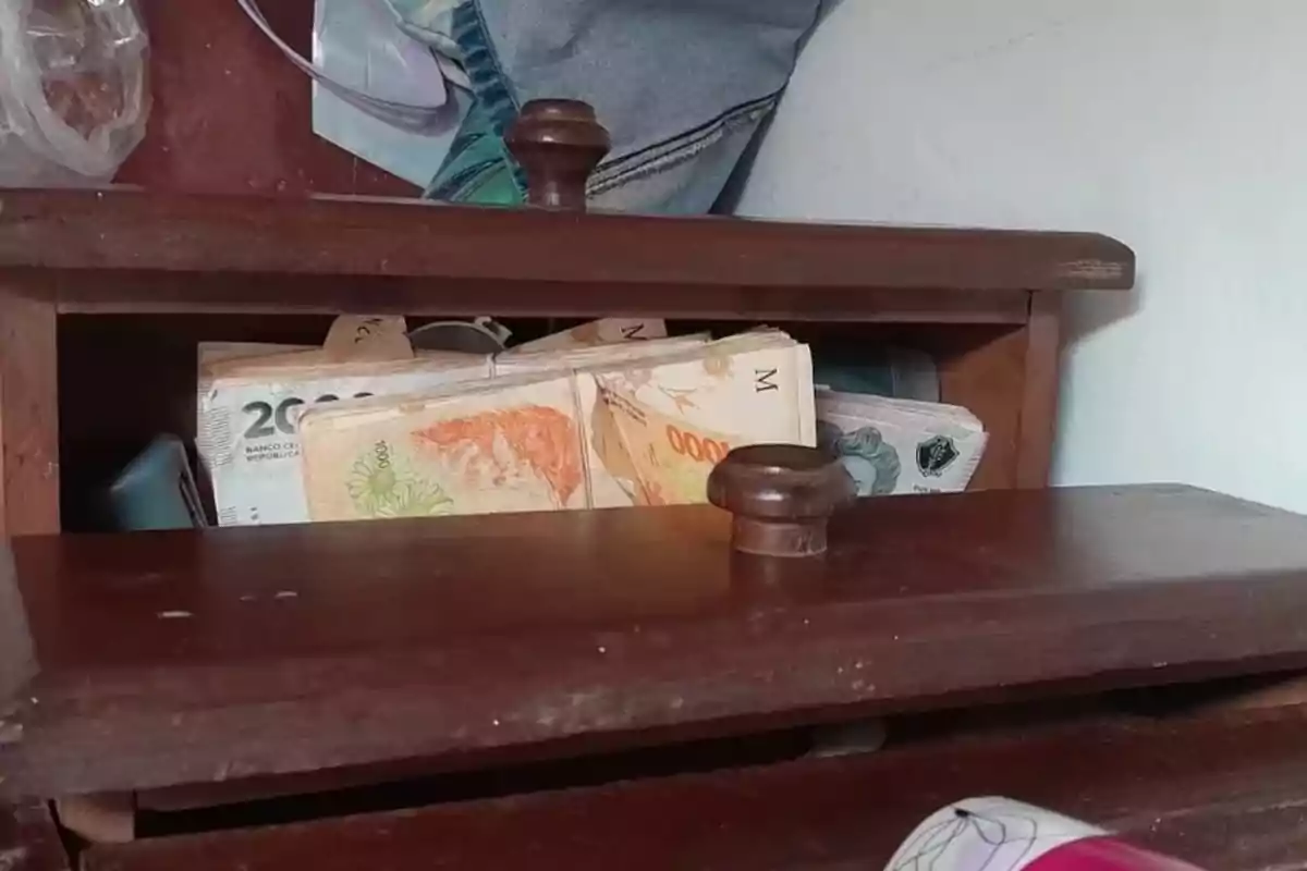 Bills of different denominations kept in a partially open wooden drawer