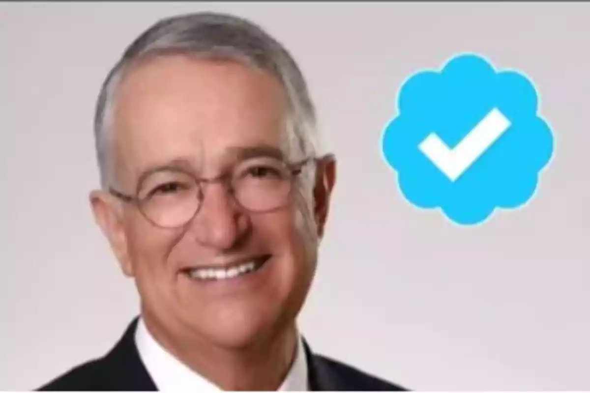 Un hombre mayor con gafas sonríe, junto a un icono de verificación azul.