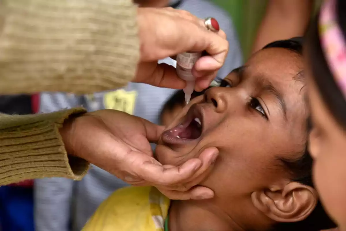 Un niño recibiendo una vacuna oral administrada por un profesional de la salud.