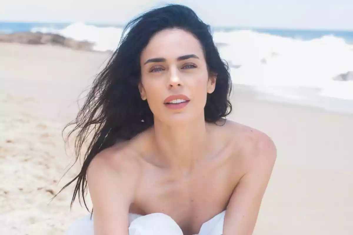 Dark-haired woman sitting on the beach with the sea in the background Dark-haired woman sitting on the beach with the sea in the background