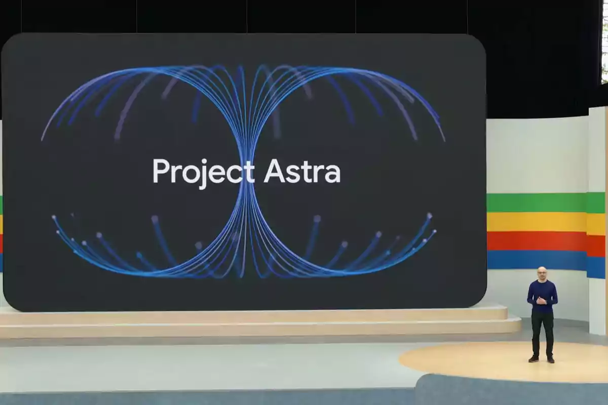A man standing on a stage next to a large screen displaying the text A man standing on a stage next to a large screen displaying the text