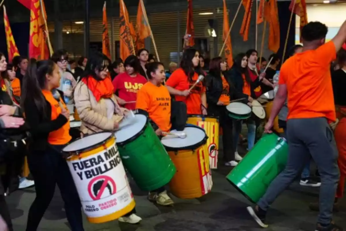 People marching and playing drums at a demonstration with orange flags and jerseys of the same color People marching and playing drums at a demonstration with orange flags and jerseys of the same color