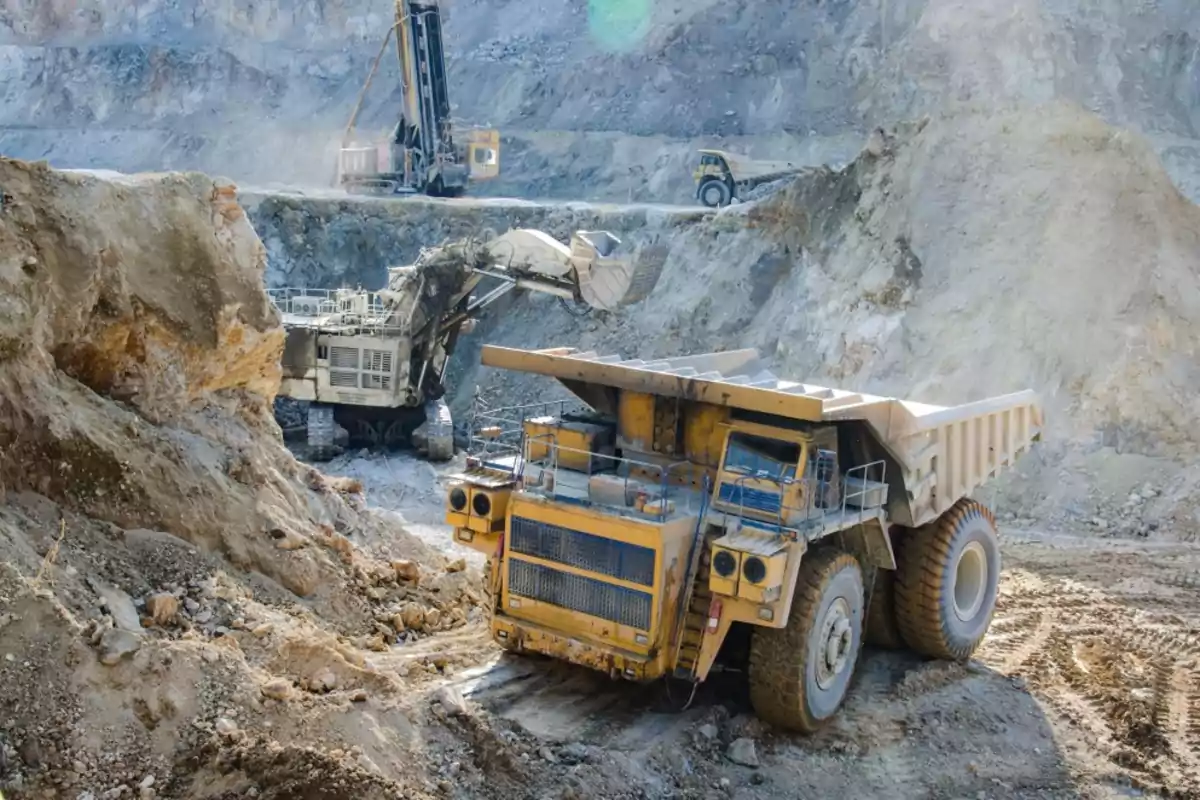Una mina a cielo abierto con maquinaria pesada trabajando en la extracción de minerales. Una mina a cielo abierto con maquinaria pesada trabajando en la extracción de minerales.