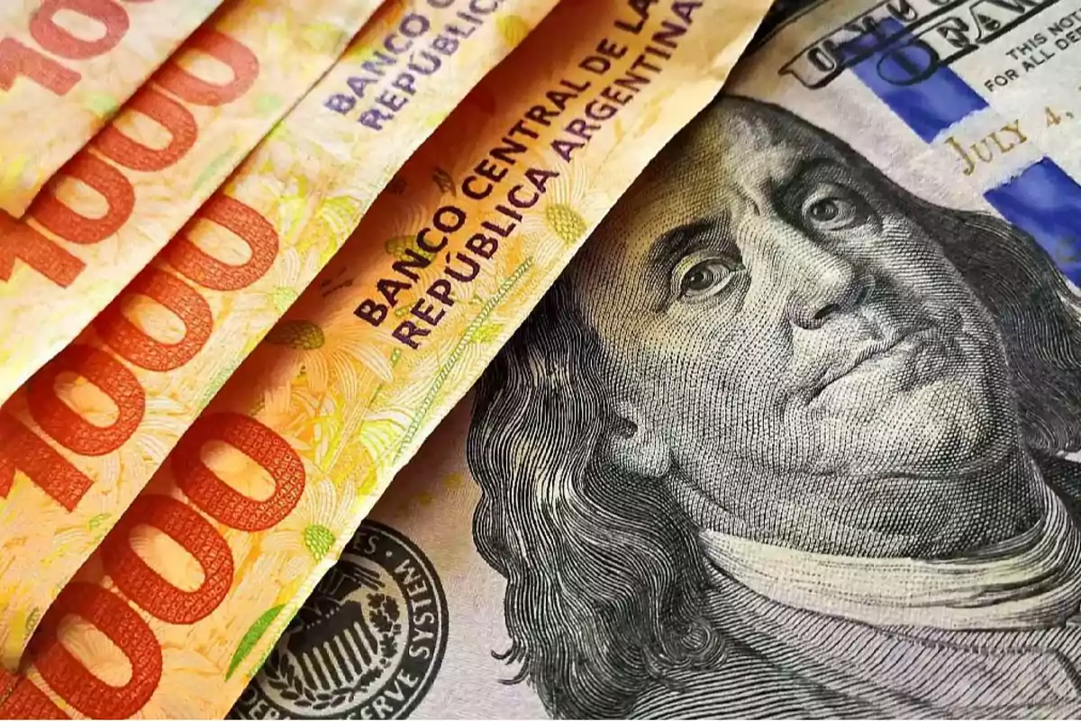 Billetes de mil pesos argentinos junto a un billete de cien dólares estadounidenses