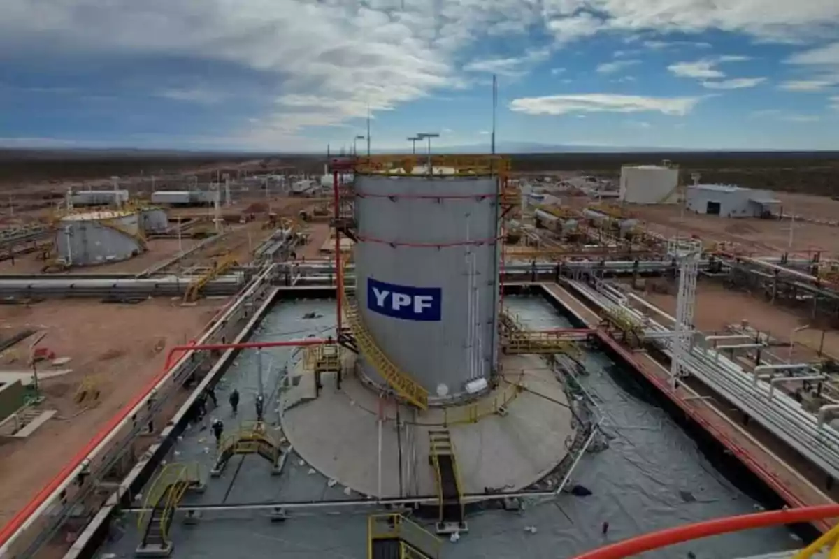 Instalaciones industriales de YPF en un paisaje desértico bajo un cielo parcialmente nublado.