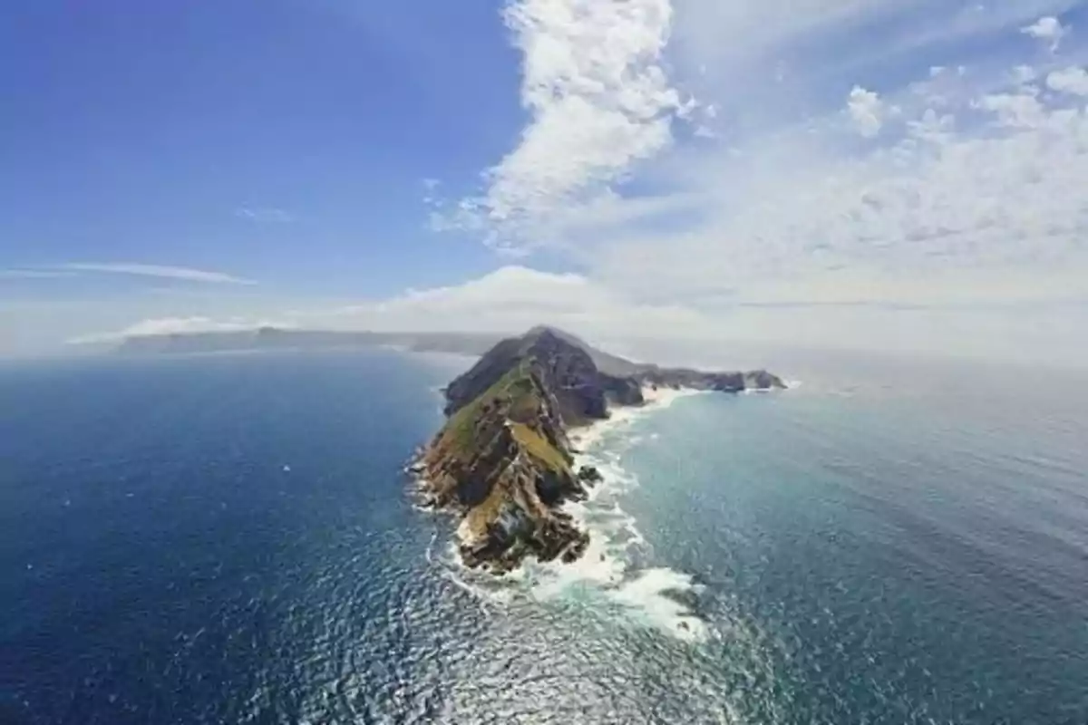 Vista aérea de una península rocosa rodeada por el océano bajo un cielo parcialmente nublado.