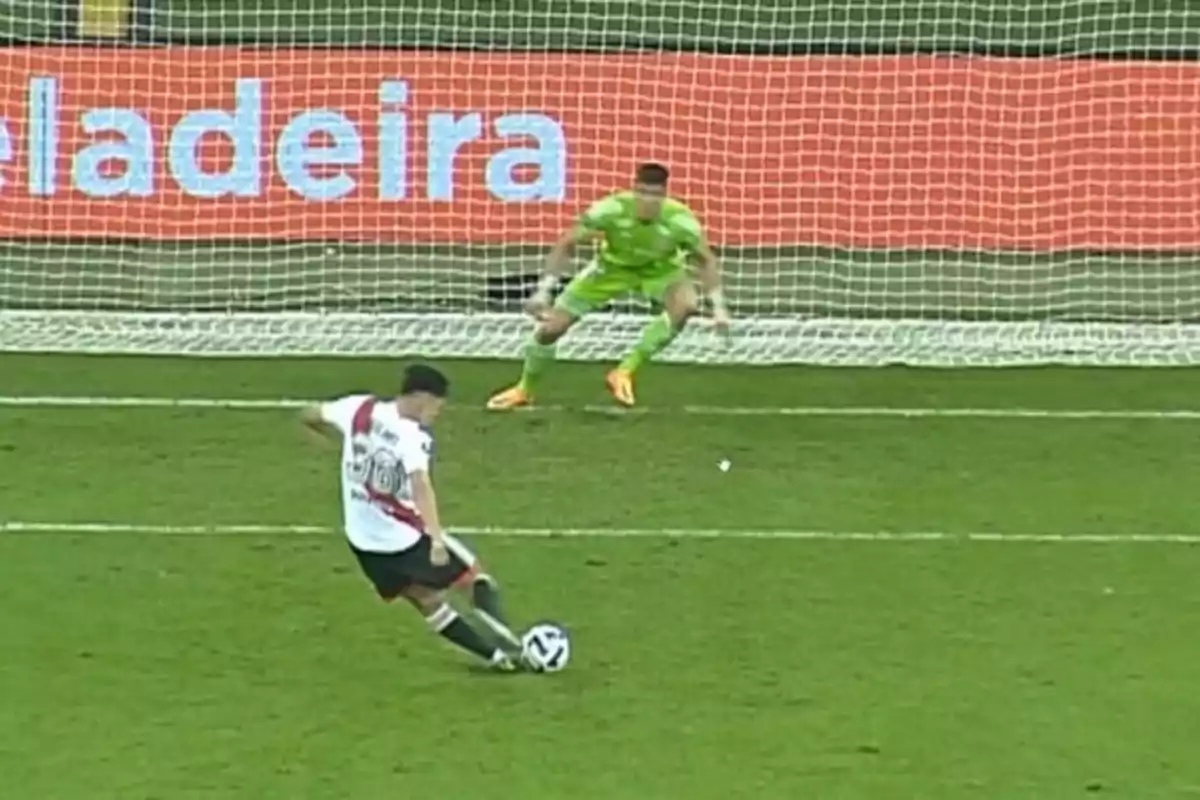 Jugador de fútbol ejecutando un penalti mientras el portero se prepara para atajar el disparo Jugador de fútbol ejecutando un penalti mientras el portero se prepara para atajar el disparo