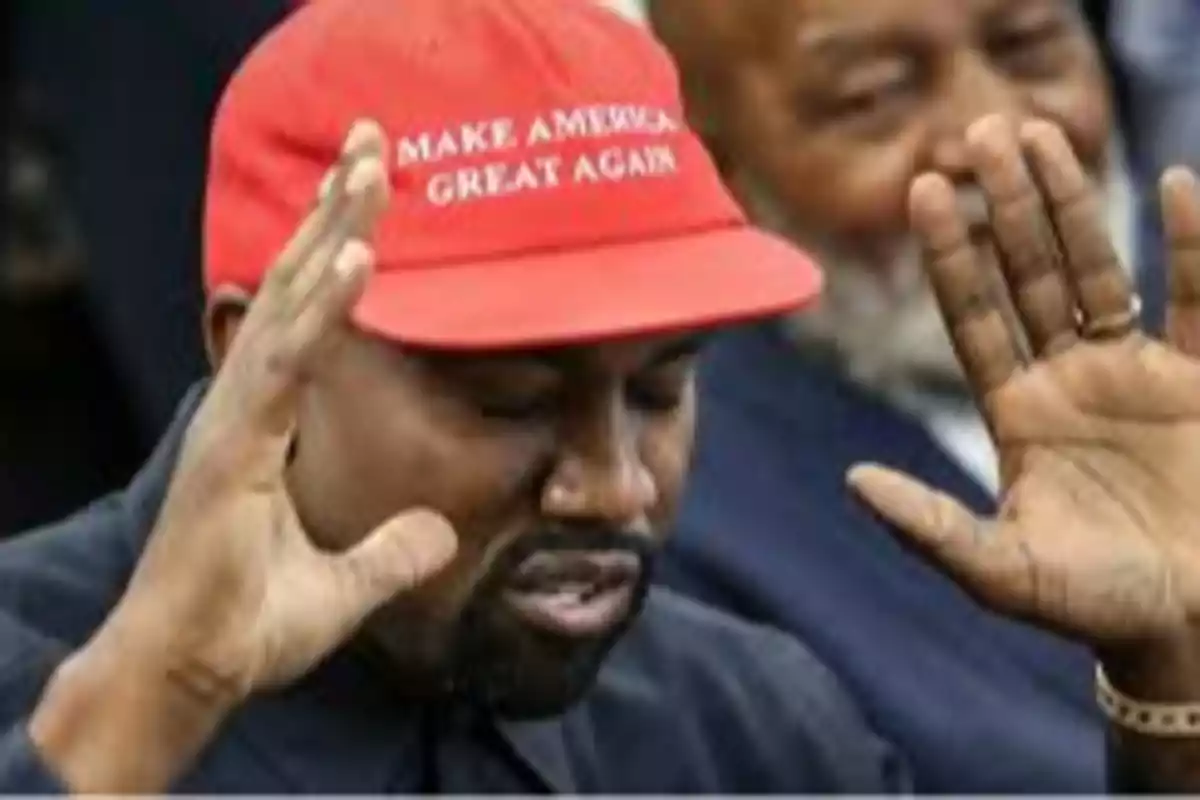 Hombre con gorra roja con las manos levantadas y los ojos cerrados.