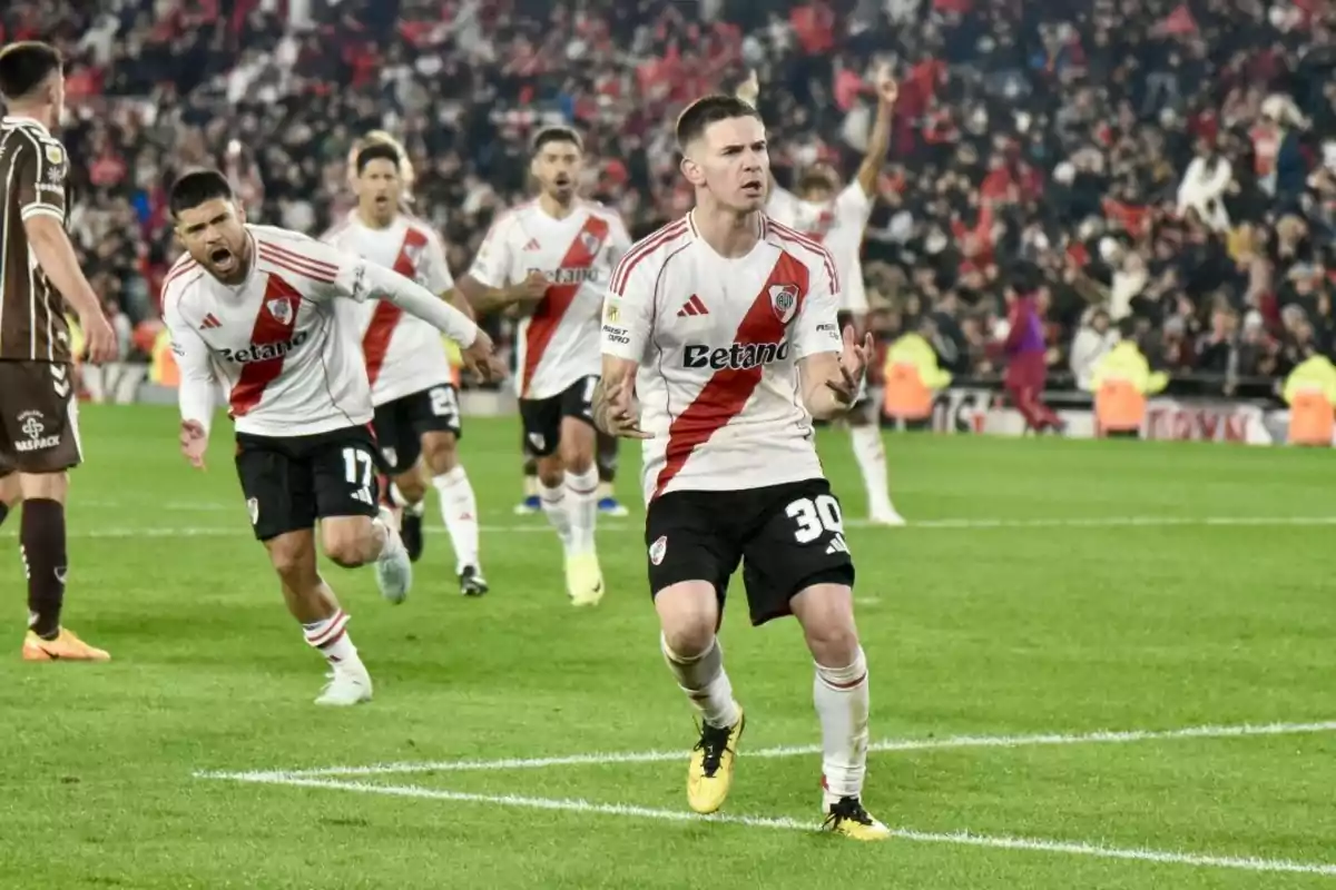 Soccer players celebrate a goal in a stadium full of spectators. Soccer players celebrate a goal in a stadium full of spectators.