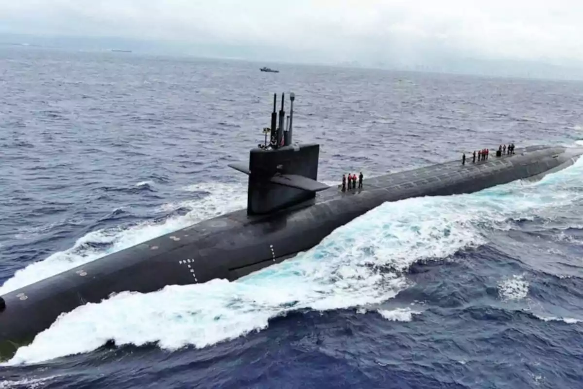 Un submarino navegando en la superficie del océano con varias personas de pie sobre su cubierta.