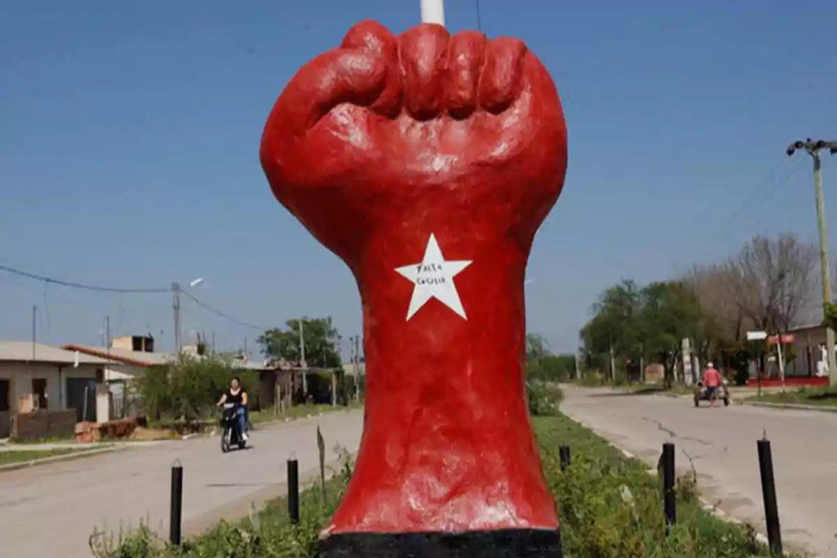 A sculpture of a raised red fist with a white star in the center located on a street in a residential area. A sculpture of a raised red fist with a white star in the center located on a street in a residential area.