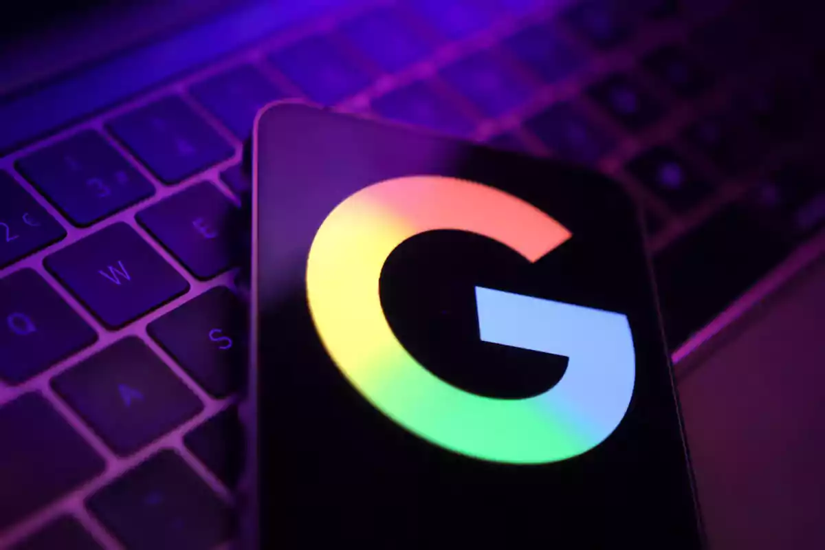 Mobile phone with the Google logo on a keyboard illuminated in purple tones. Mobile phone with the Google logo on a keyboard illuminated in purple tones.