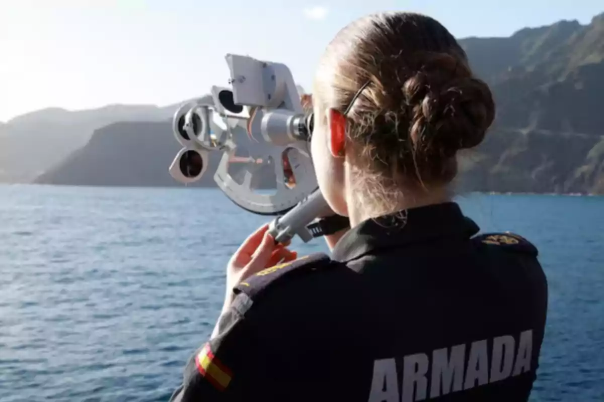 Mujer de la armada usando un sextante para navegación en el mar con montañas al fondo Mujer de la armada usando un sextante para navegación en el mar con montañas al fondo