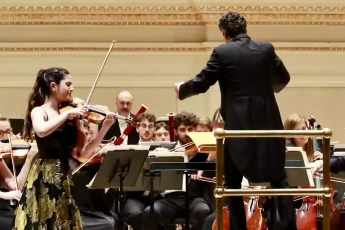 A violinist plays with an orchestra while the conductor leads the performance on an elegant stage. A violinist plays with an orchestra while the conductor leads the performance on an elegant stage.
