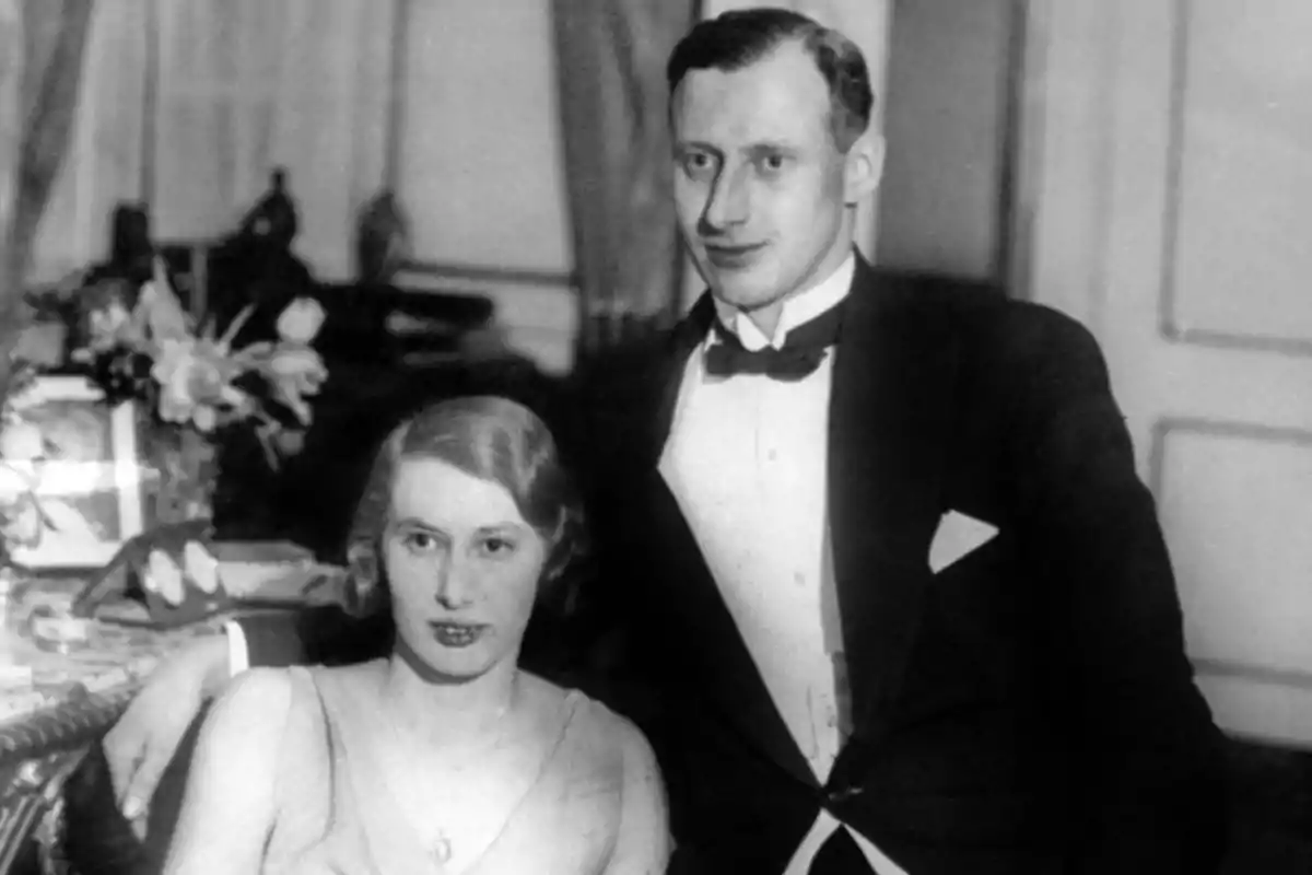 Pareja elegante de los años 30 posando en una sala decorada con flores