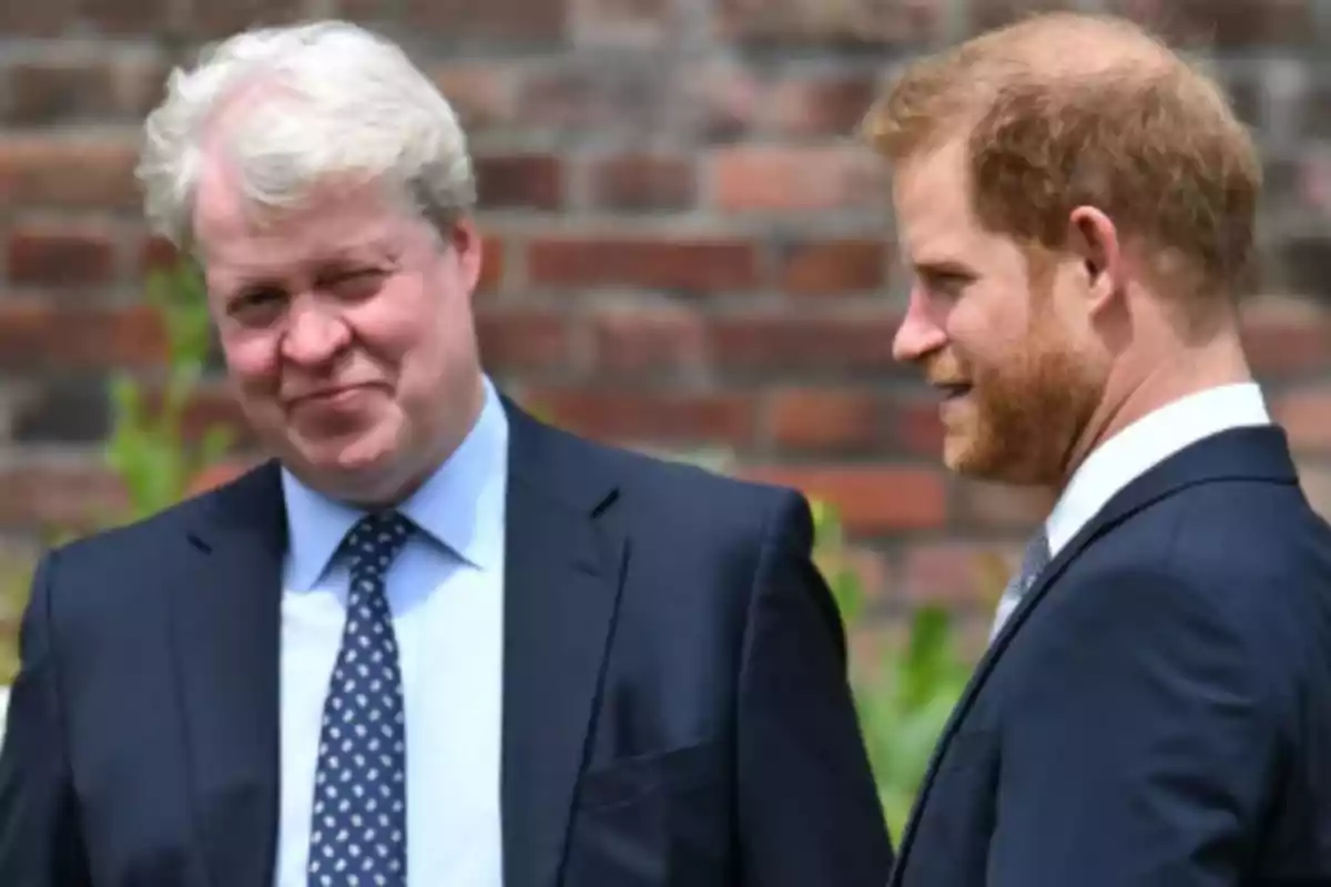 Two men dressed in suits talk outdoors in front of a brick wall. Two men dressed in suits talk outdoors in front of a brick wall.