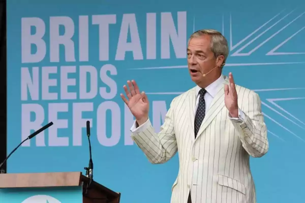 A man on a stage speaking in front of a microphone with a background that says A man on a stage speaking in front of a microphone with a background that says