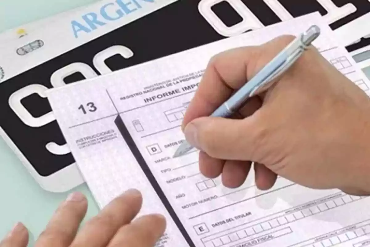 Una persona completa un formulario junto a una matrícula de vehículo. Una persona completa un formulario junto a una matrícula de vehículo.