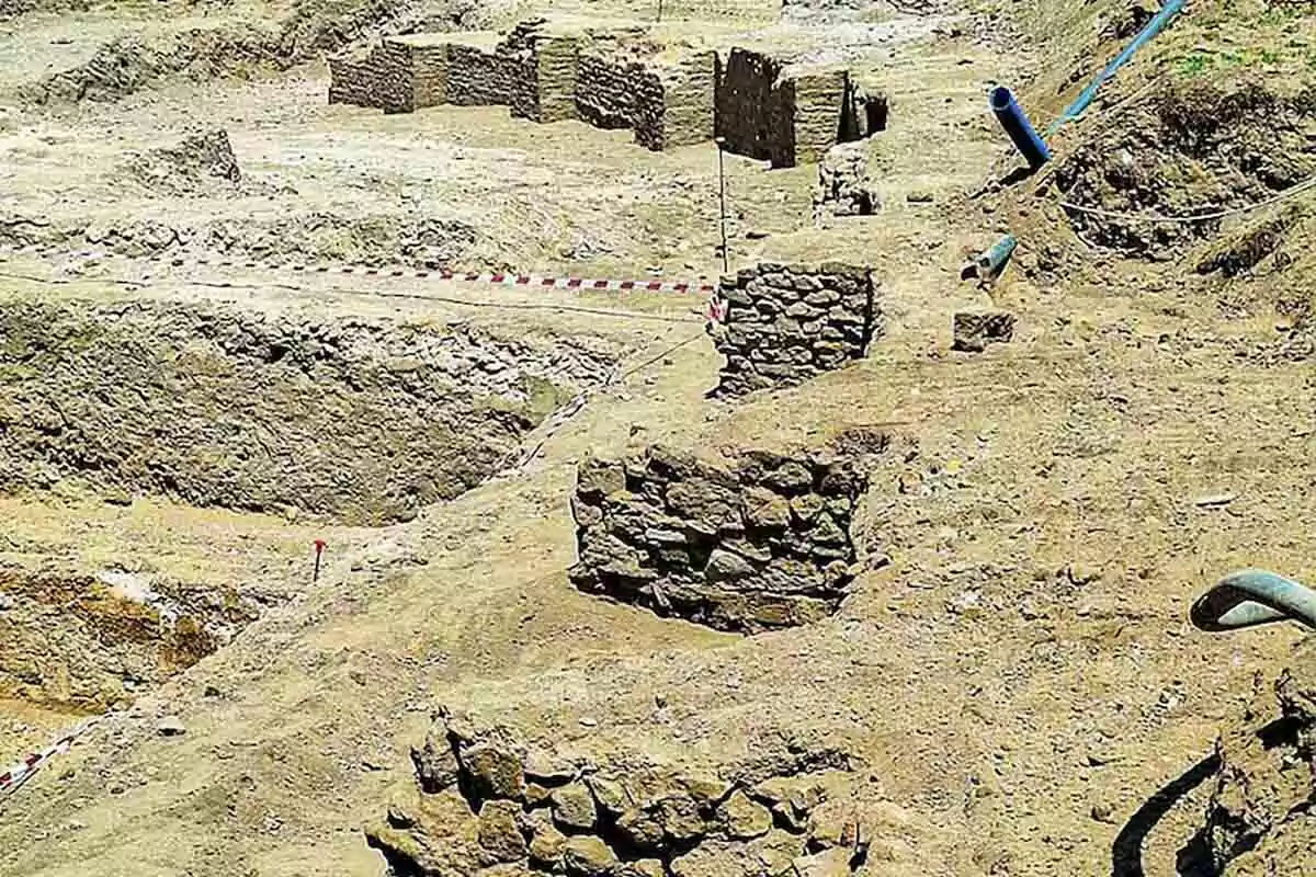 Excavación arqueológica con estructuras de piedra parcialmente expuestas en un terreno arenoso. Excavación arqueológica con estructuras de piedra parcialmente expuestas en un terreno arenoso.