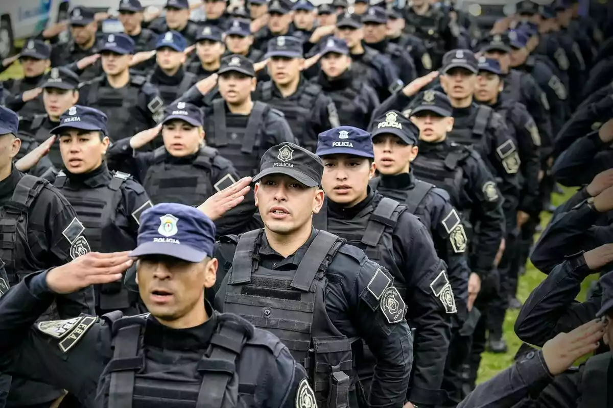 Un grupo de policías uniformados realiza un saludo militar en formación.